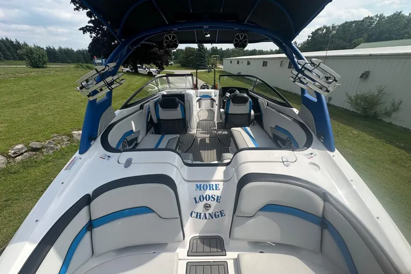 Slide: The Image of 2018 Yamaha 242 X boat interior with blue accents, parked on grass. - 8