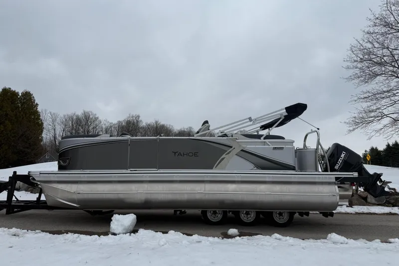 Slide: The Image of 2025 Tahoe 2185 pontoon boat on trailer, parked on snowy road. - 6