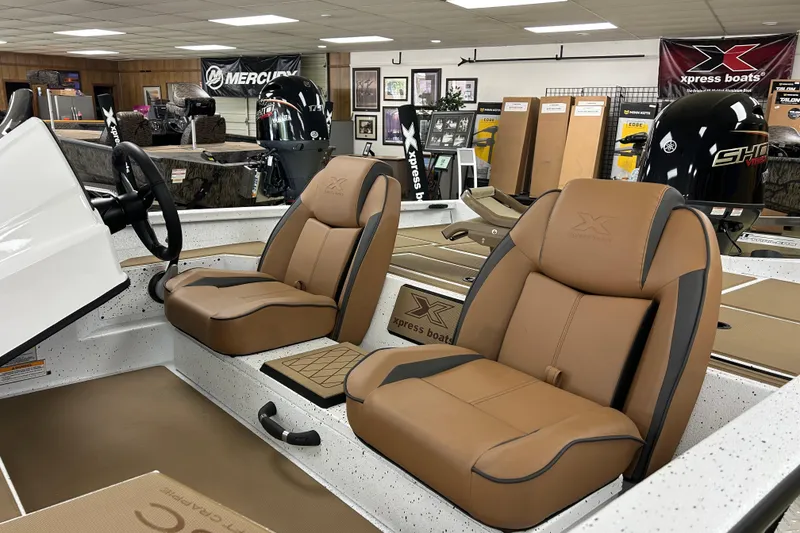 Slide: The Image of 2026 Xpress H18C Crappie boat interior with tan seats and Mercury engine display. - 4