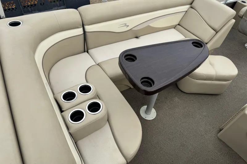 Slide: The Image of 2012 Bennington 24 SF boat interior with beige seating and a dark wood table. - 20
