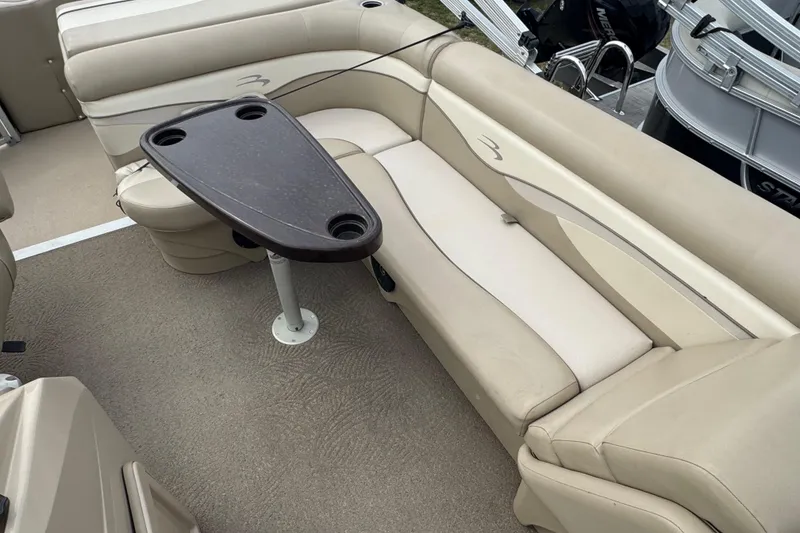 Slide: The Image of 2012 Bennington 24 SF boat interior with beige seating and a central table. - 9