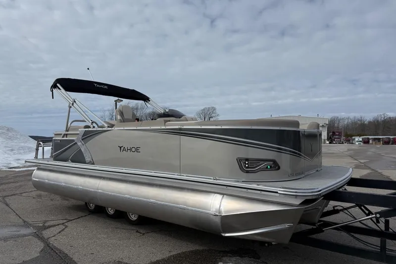 Slide: The Image of 2025 Tahoe 2185 pontoon boat with sleek design on a trailer, under a cloudy sky. - 7