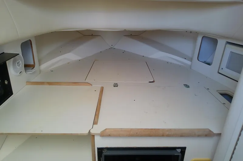 Slide: The Image of 2001 Boston Whaler 28 Outrage cabin interior with beige cushions and compact design. - 35