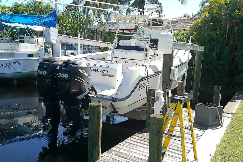 Slide: The Image of 2001 Boston Whaler 28 Outrage boat with T-top and rod holders, surrounded by palm trees. - 5
