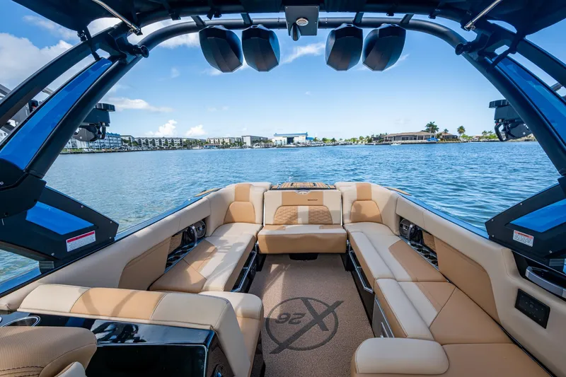 Slide: The Image of 2022 MasterCraft X26 boat interior with luxurious seating on a scenic lake. - 12