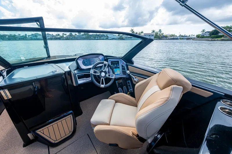 Slide: The Image of 2022 MasterCraft X26 boat interior with steering wheel and captain's chair on a lake. - 18