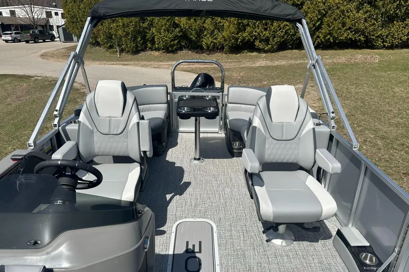 Slide: The Image of 2025 Tahoe 2185 boat interior with modern seating and steering wheel, parked on grass. - 14