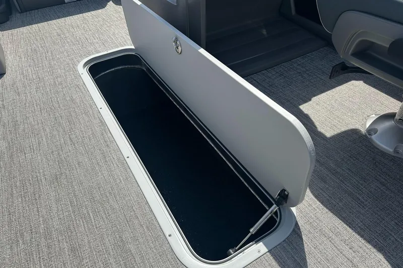 Slide: The Image of 2025 Tahoe 2185 boat storage compartment with open hatch on carpeted floor. - 25