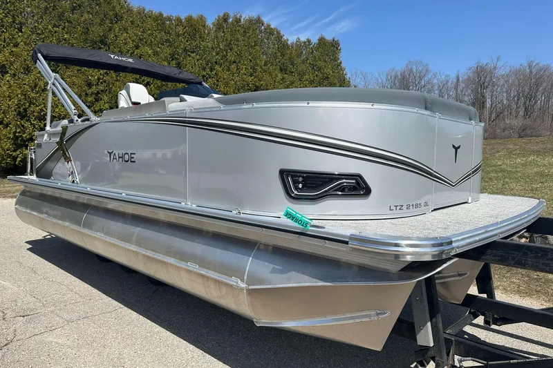 Slide: The Image of 2025 Tahoe 2185 pontoon boat on trailer, silver exterior, parked outdoors. - 3