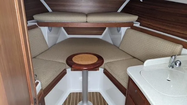 Slide: The Image of 2011 Back Cove 30 cabin interior with cozy seating, wooden accents, and compact sink area. - 9