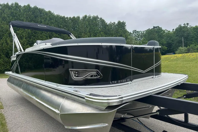 Slide: The Image of 2025 Tahoe 2185 pontoon boat on trailer, sleek black design, parked outdoors. - 11