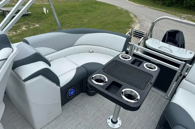 Slide: The Image of 2025 Tahoe 2185 boat interior with gray seating and a table featuring cup holders. - 26