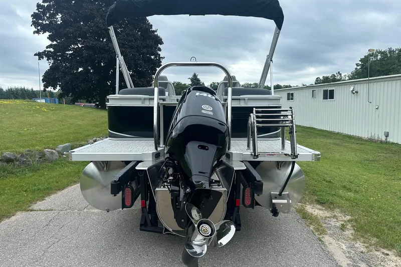 Slide: The Image of 2025 Tahoe 2185 pontoon boat with outboard motor, parked on a paved path. - 5