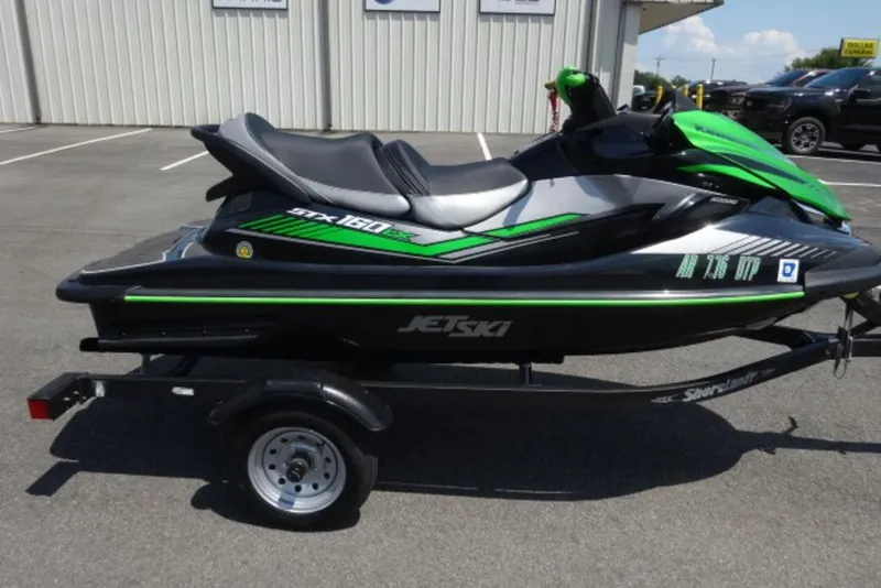 Slide: The Image of 2020 Kawasaki STX160 jet ski on trailer, green and black design, parked outdoors. - 3