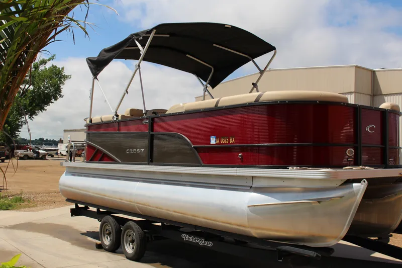 The Image of 2023 Crest 220 SLS Classic pontoon boat on trailer, red exterior, parked outdoors. - 1