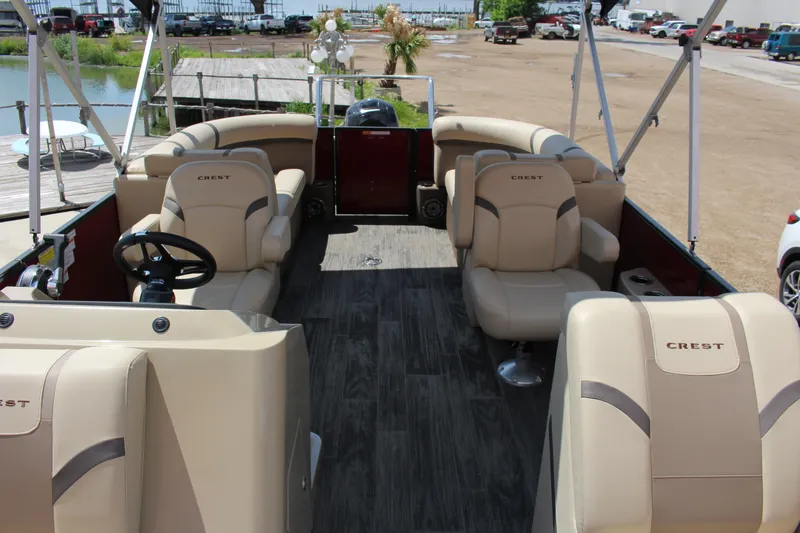 Slide: The Image of 2023 Crest 220 SLS Classic pontoon boat interior with beige seating and steering wheel. - 9