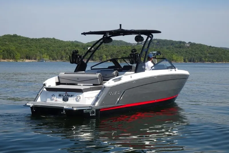 Slide: The Image of 2026 Cobalt R8 Surf boat on a serene lake with lush green hills. - 2