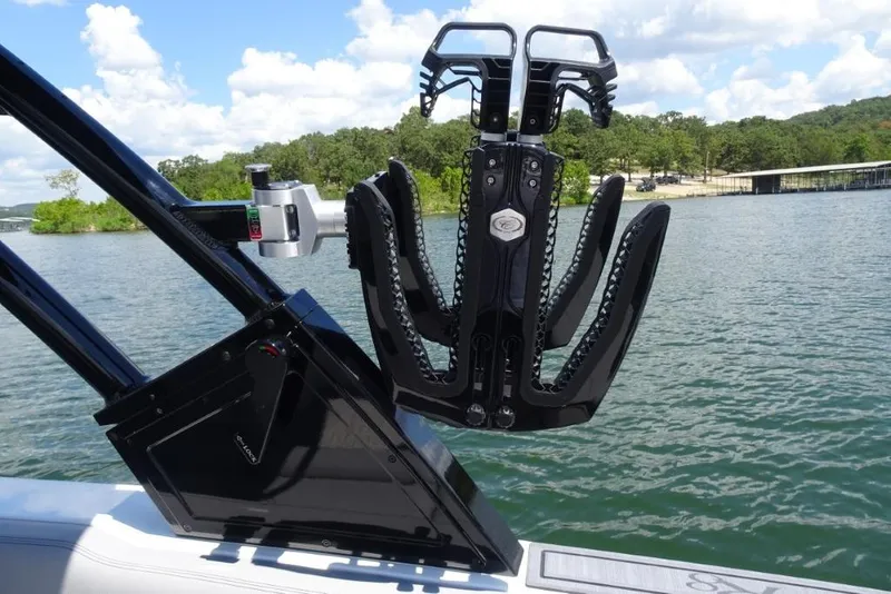 Slide: The Image of 2026 Cobalt R8 Surf boat with a mounted wakeboard rack on a scenic lake. - 28
