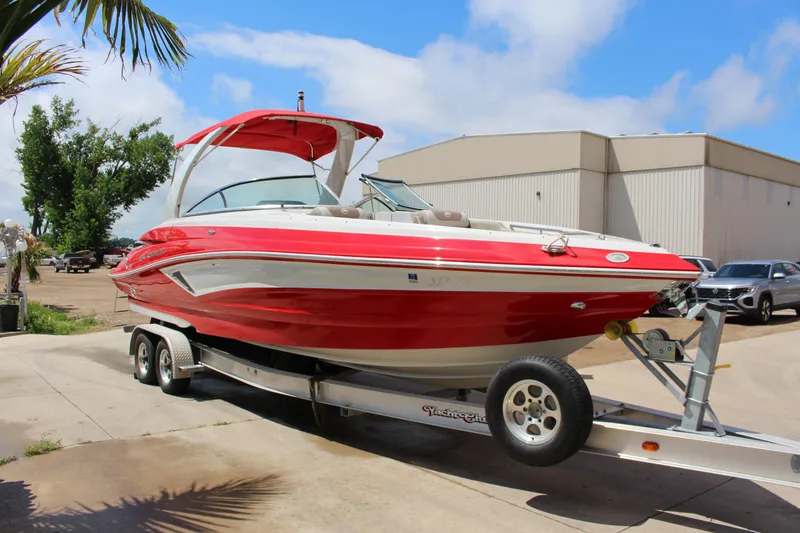 Slide: The Image of 2023 Crownline 290 SS boat on trailer, vibrant red, parked outdoors. - 1
