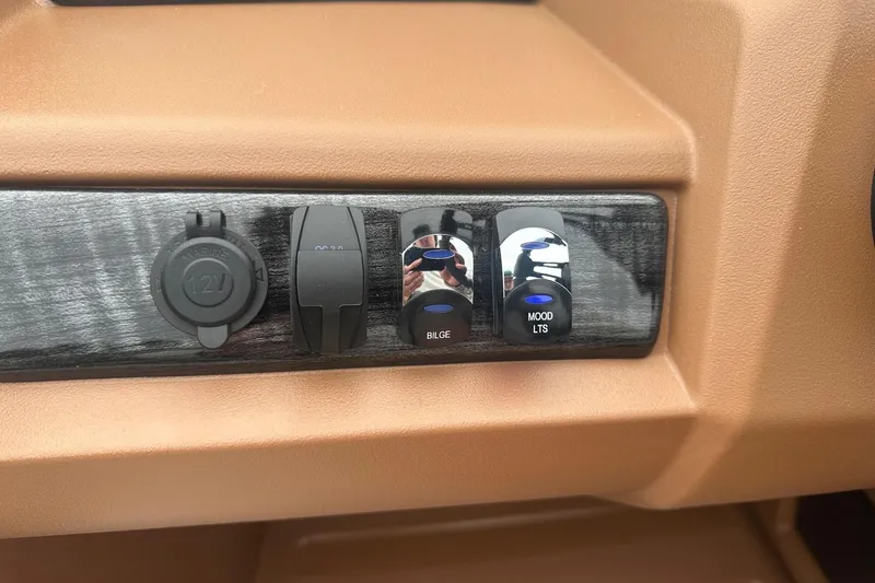 Slide: The Image of Dashboard controls of 2025 Tahoe 2185 boat, featuring switches and a 12V outlet. - 19