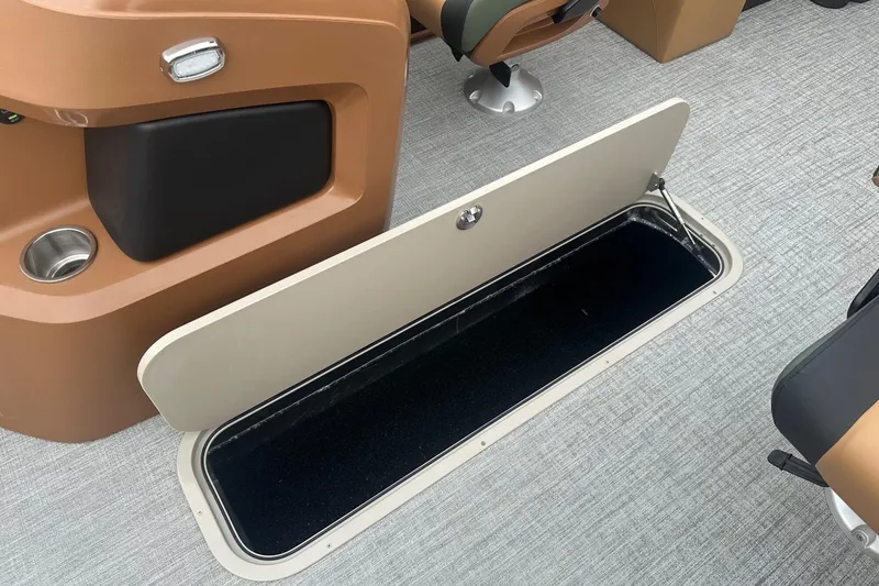 Slide: The Image of Open storage compartment in 2025 Tahoe 2185 boat interior, featuring brown and black seating. - 22