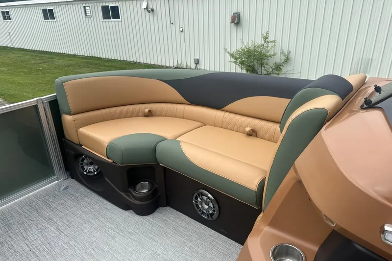 Slide: The Image of 2025 Tahoe 2185 boat interior with tan and green seating, cup holders, and speakers. - 27