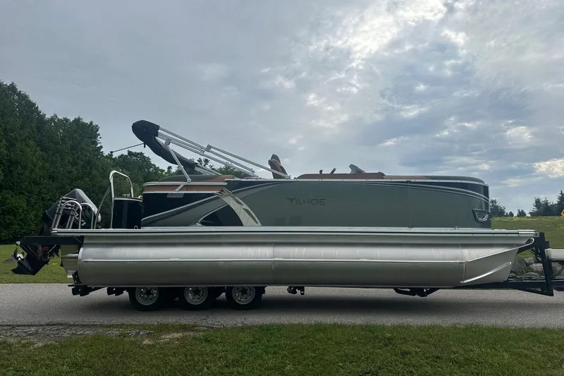 Slide: The Image of 2025 Tahoe 2185 pontoon boat on trailer, parked on a road with cloudy sky. - 7