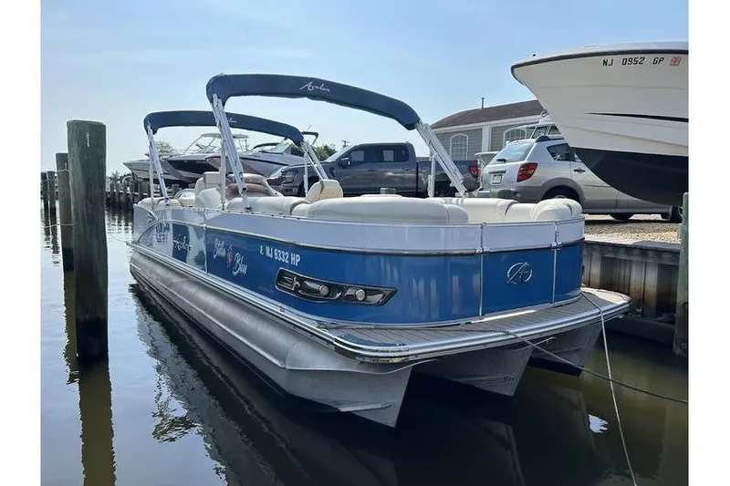 Slide: The Image of 2021 Avalon 2785 pontoon boat docked, featuring blue and white design with canopy. - 1