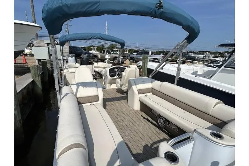 Slide: The Image of 2021 Avalon 2785 pontoon boat with spacious seating and blue canopy in marina. - 2