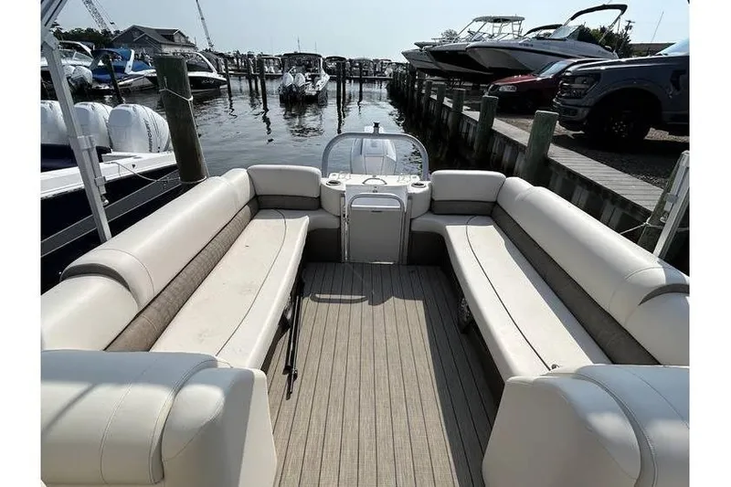 Slide: The Image of 2021 Avalon 2785 pontoon boat interior with beige seating at a marina. - 3