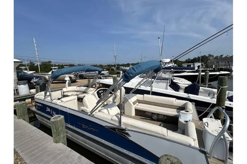 Slide: The Image of 2021 Avalon 2785 pontoon boat docked, featuring blue and white design with comfortable seating. - 7