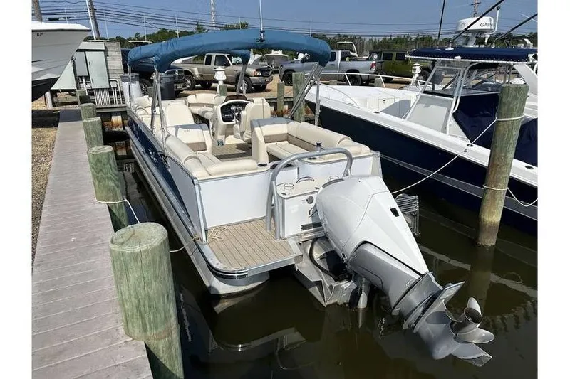 Slide: The Image of 2021 Avalon 2785 pontoon boat docked, featuring a blue canopy and powerful outboard motor. - 8