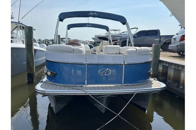 Slide: The Image of 2021 Avalon 2785 pontoon boat docked, featuring blue exterior and white seating. - 9