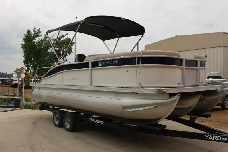 The Image of 2022 Barletta C22UC pontoon boat on trailer, parked outdoors near a building. - 1
