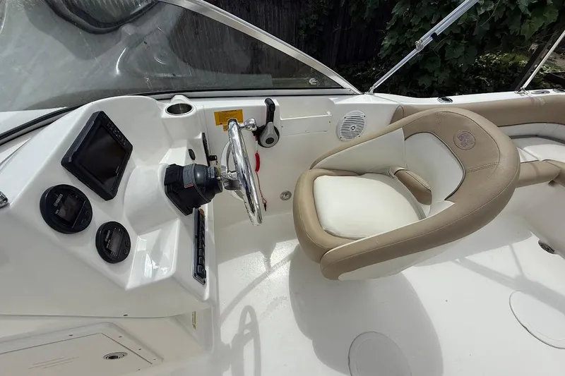 Slide: The Image of 2019 Key West 203 DFS boat cockpit with steering wheel and beige seating. - 11