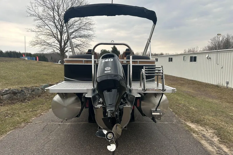 Slide: The Image of 2025 Tahoe 2185 pontoon boat with powerful outboard motor, parked on a paved path. - 4