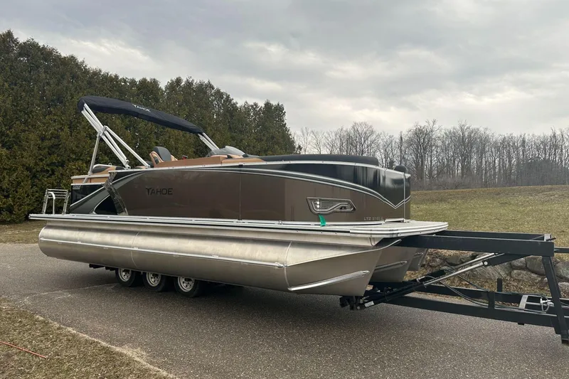 Slide: The Image of 2025 Tahoe 2185 pontoon boat on trailer, parked outdoors on a cloudy day. - 8