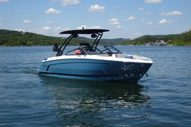 The Image of 2026 Cobalt R8 Surf boat on a serene lake under a clear blue sky. - 0
