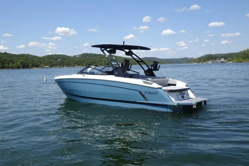 Slide: The Image of 2026 Cobalt R8 Surf boat on a serene lake under a clear blue sky. - 3