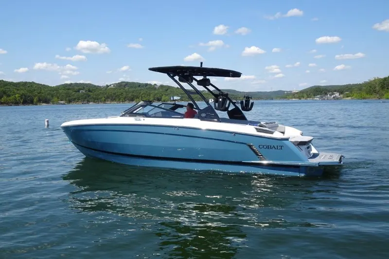 Slide: The Image of 2026 Cobalt R8 Surf boat on a serene lake under a clear blue sky. - 4