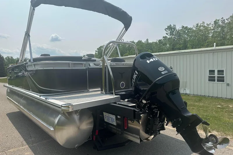 Slide: The Image of 2025 Tahoe 2185 pontoon boat with Suzuki 140 outboard motor, parked outdoors. - 3