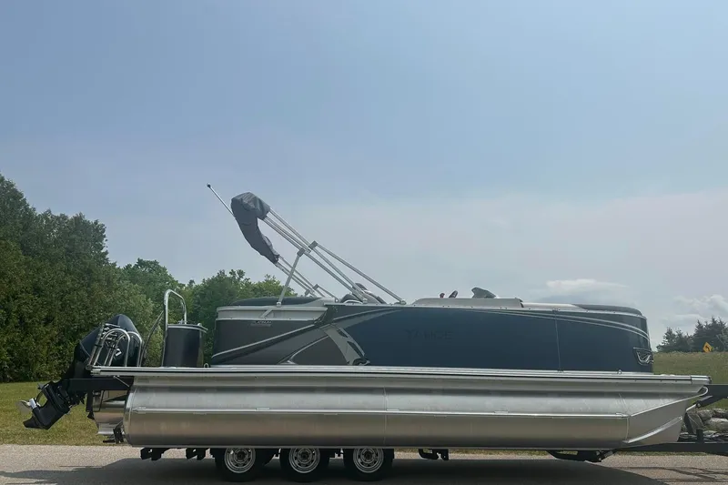 Slide: The Image of 2025 Tahoe 2185 pontoon boat on trailer, parked outdoors under clear sky. - 5