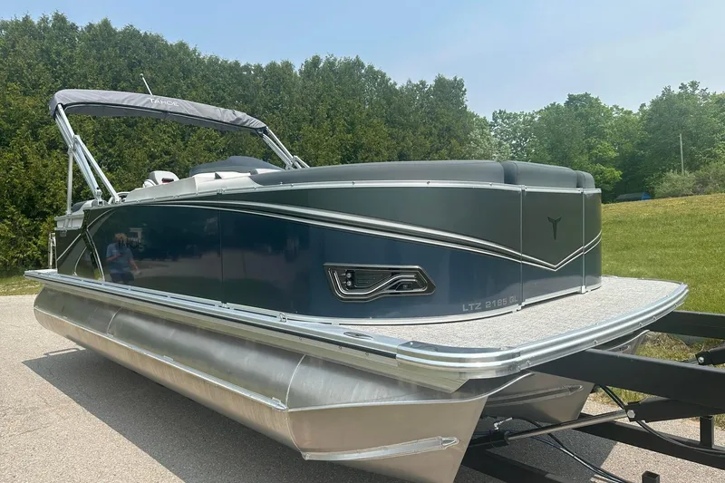 Slide: The Image of 2025 Tahoe 2185 pontoon boat on trailer, surrounded by greenery. - 6