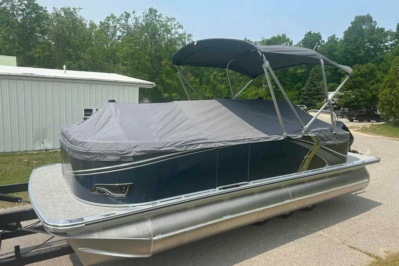 Slide: The Image of 2025 Tahoe 2185 pontoon boat with cover, parked outdoors on a sunny day. - 8