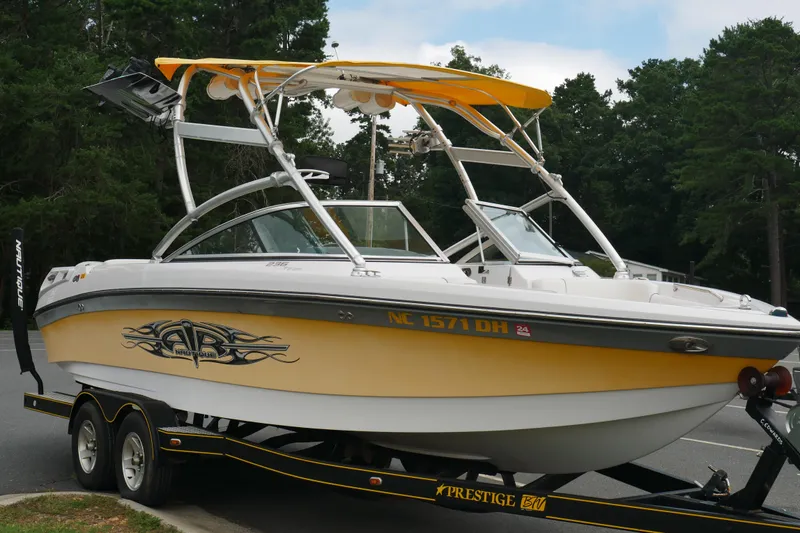 Slide: The Image of 2007 Correct Craft 236 Team Edition boat on trailer, yellow and white design, parked outdoors. - 2