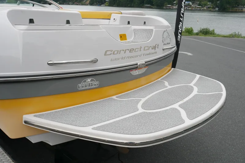 Slide: The Image of 2007 Correct Craft 236 Team Edition boat with swim platform, docked by a lake. - 29