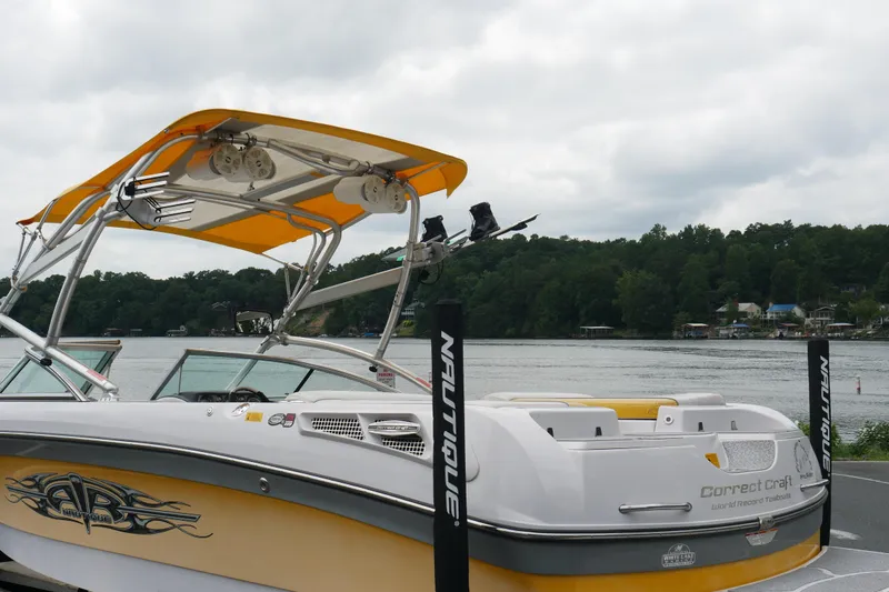 Slide: The Image of 2007 Correct Craft 236 Team Edition boat with yellow canopy on a scenic lake. - 3