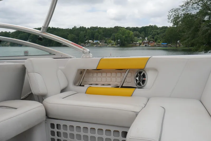 Slide: The Image of 2007 Correct Craft 236 Team Edition boat interior with white and yellow seating by a lake. - 6