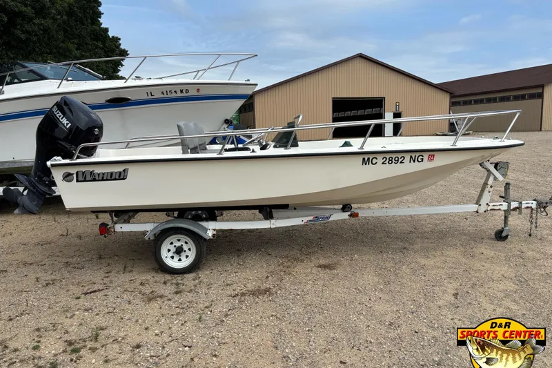 Slide: The Image of 1986 Wahoo 16.2 boat on trailer, Suzuki outboard, parked near a storage building. - 3