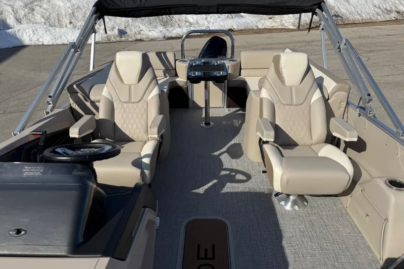 Slide: The Image of 2025 Tahoe 2385 boat interior with beige seating and steering wheel, parked on pavement. - 13